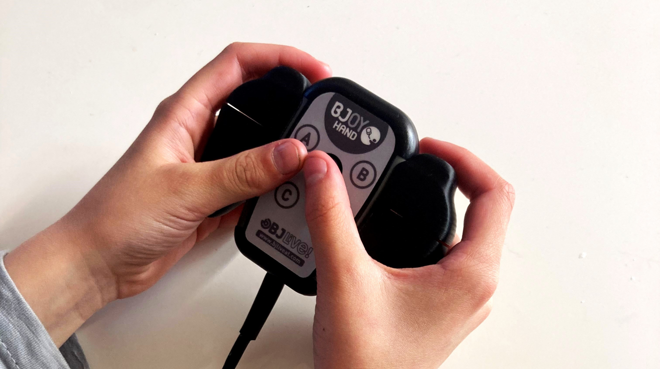 Två händer håller i en joystick i ett TV-spelsformat hölje