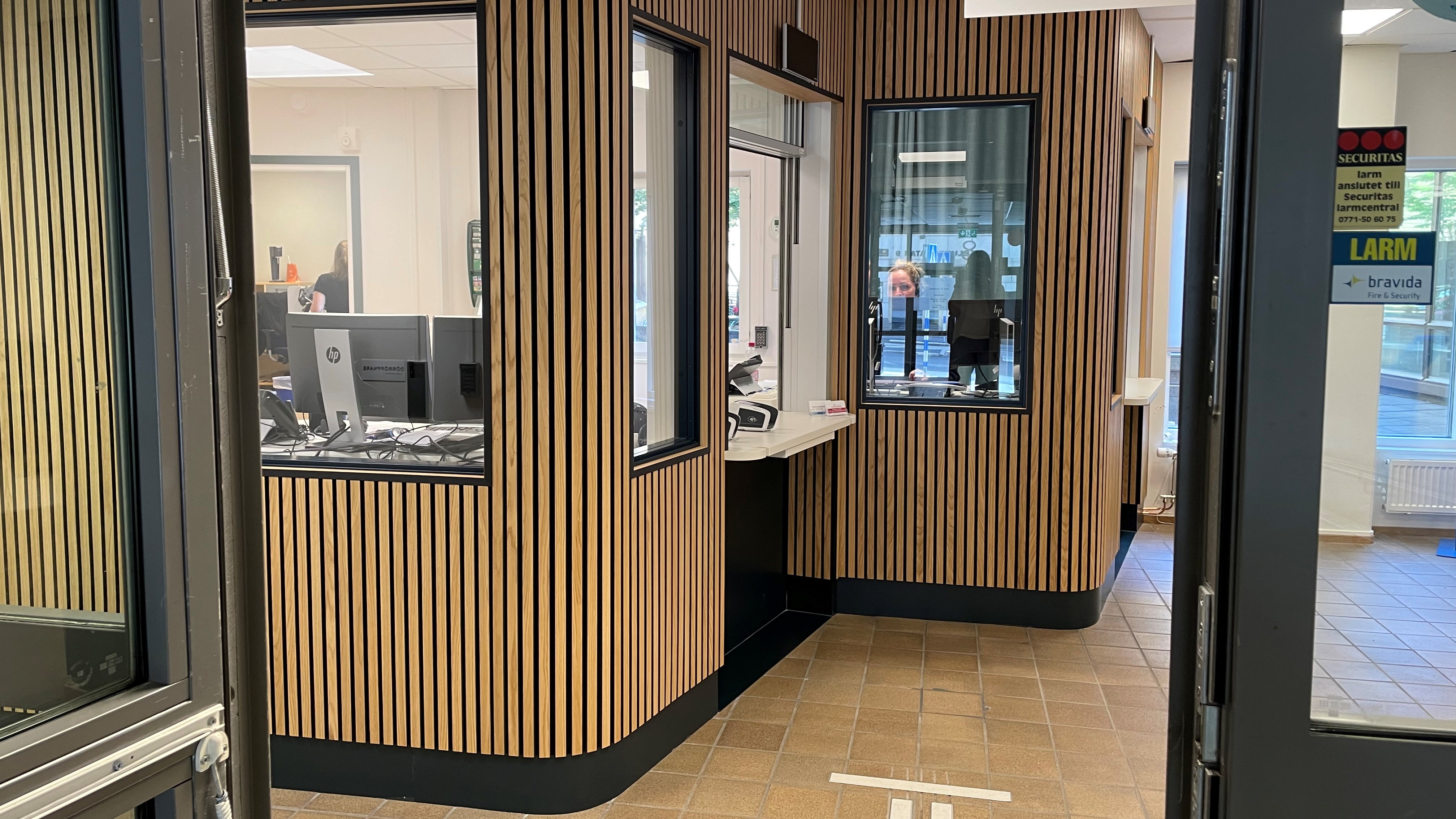 Inbyggd receptionen med fönster för att anmäla sig. Täckt av träpanel.
