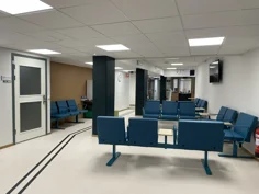 Väntrummet med blå sittmöbler och vitt golv med ledstråk.