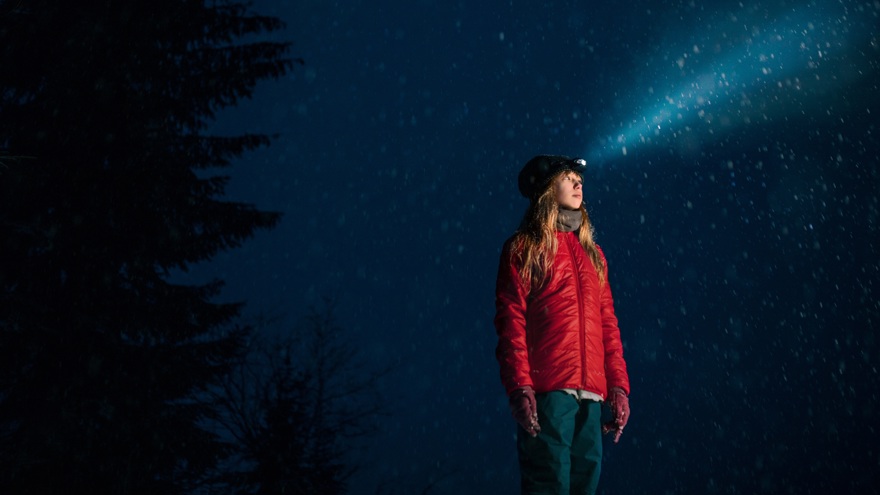 Flicka med pannlampa och stjärnhimmel ovanför