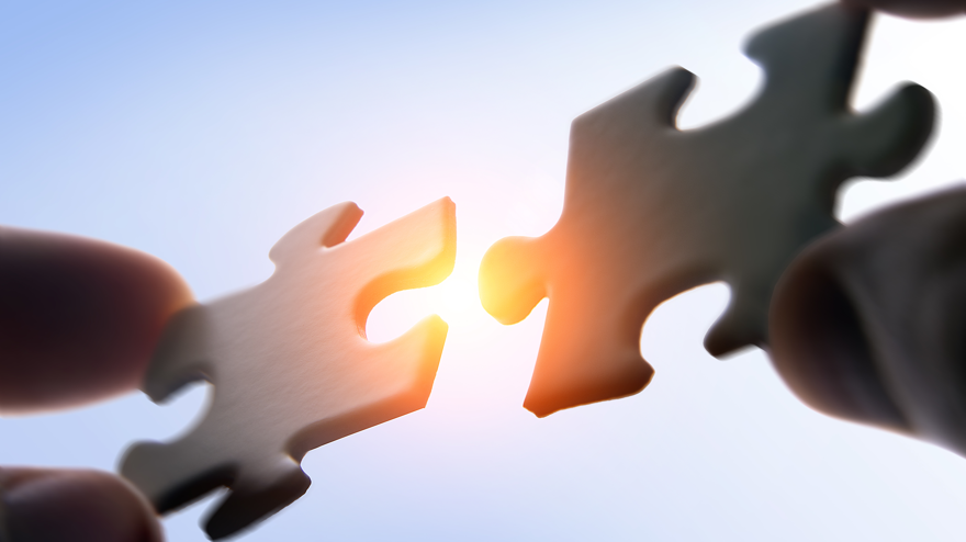Putting puzzle pieces together on sky background with sunligh