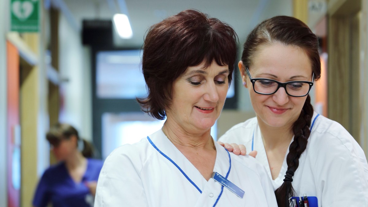 Två sjuksköterskor i en sjukhuskorridor