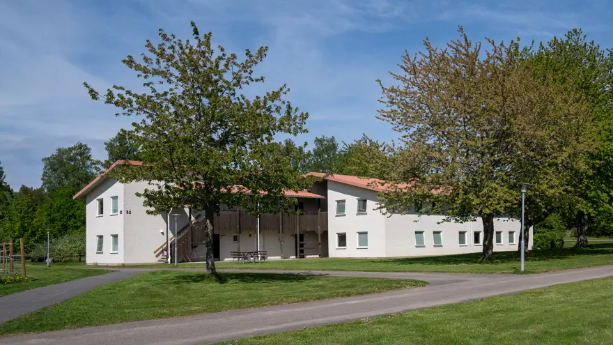 Tvåvånings-internatboende omgivet av gräs, småvägar och lummiga träd