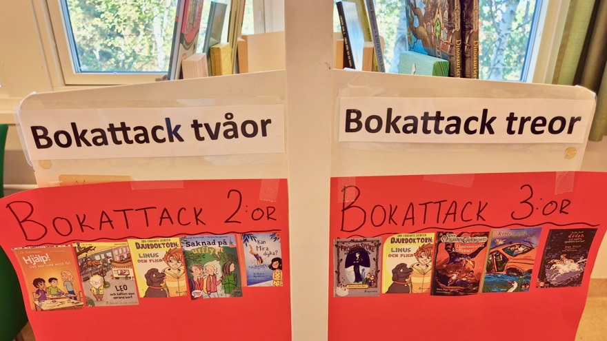 Två röda skyltar med rubrikerna Bokattack tvåor och Bokattack treor. På skyltarna är olika bokomslag klistrade.