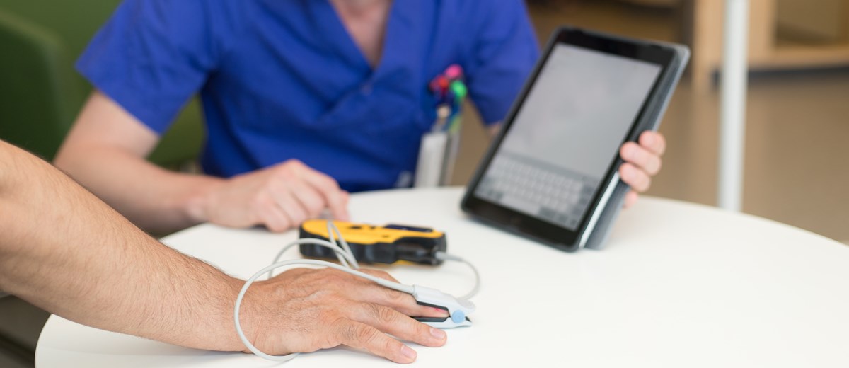 Patient med mätutrustning på ett finger.