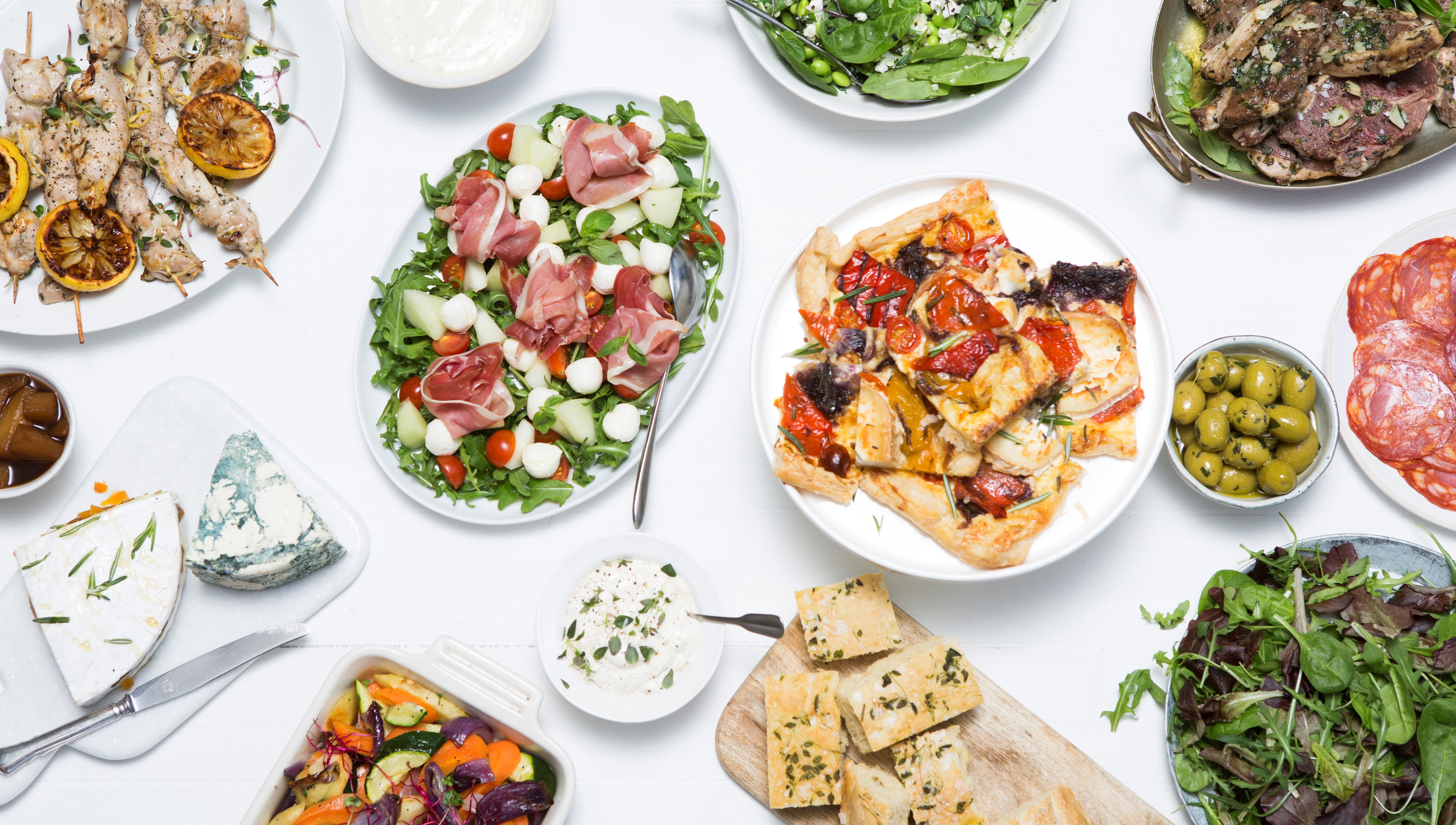 Olika fat fyllda med cateringmat som pizza, sallad, kycklingspett, bröd med mera