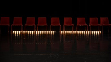 En rad röda stolar på en scen med belysning underifrån.