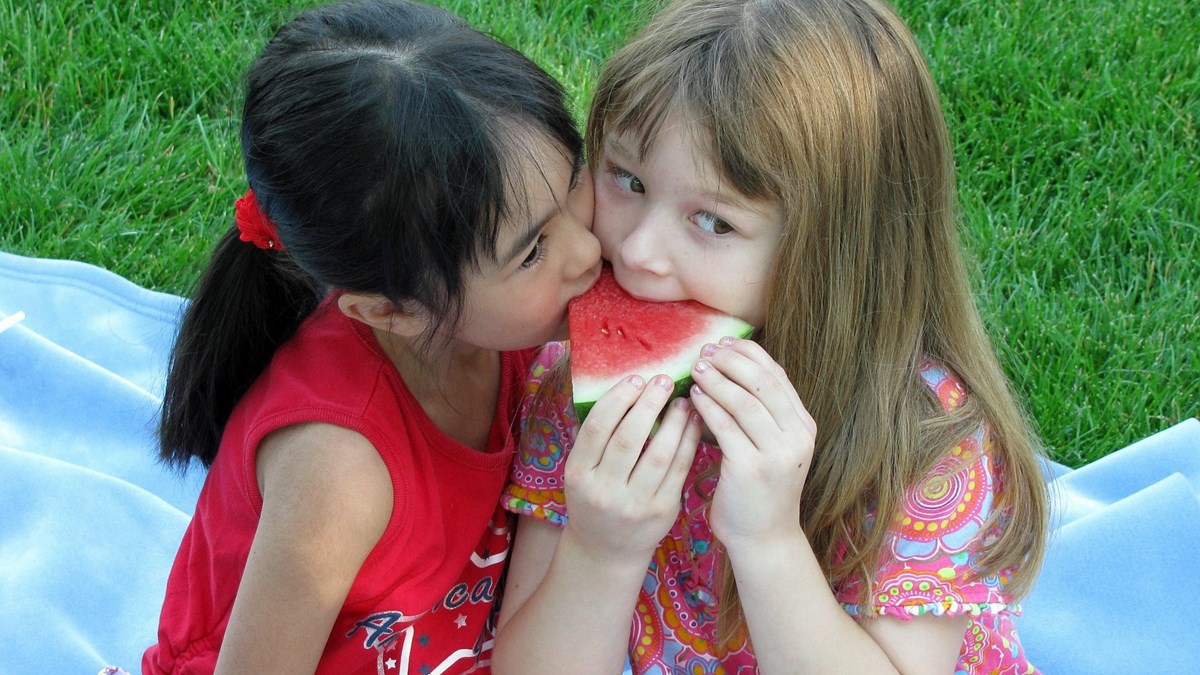 Två flickor äter melon.