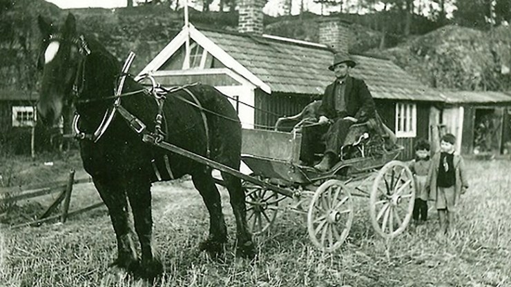 svartvitt foto av häst och vagn med lite folk kring