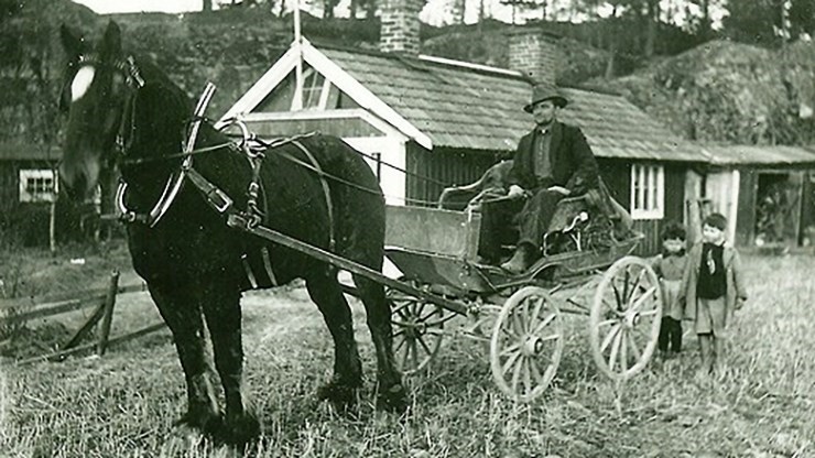 svartvitt foto av häst och vagn med lite folk kring