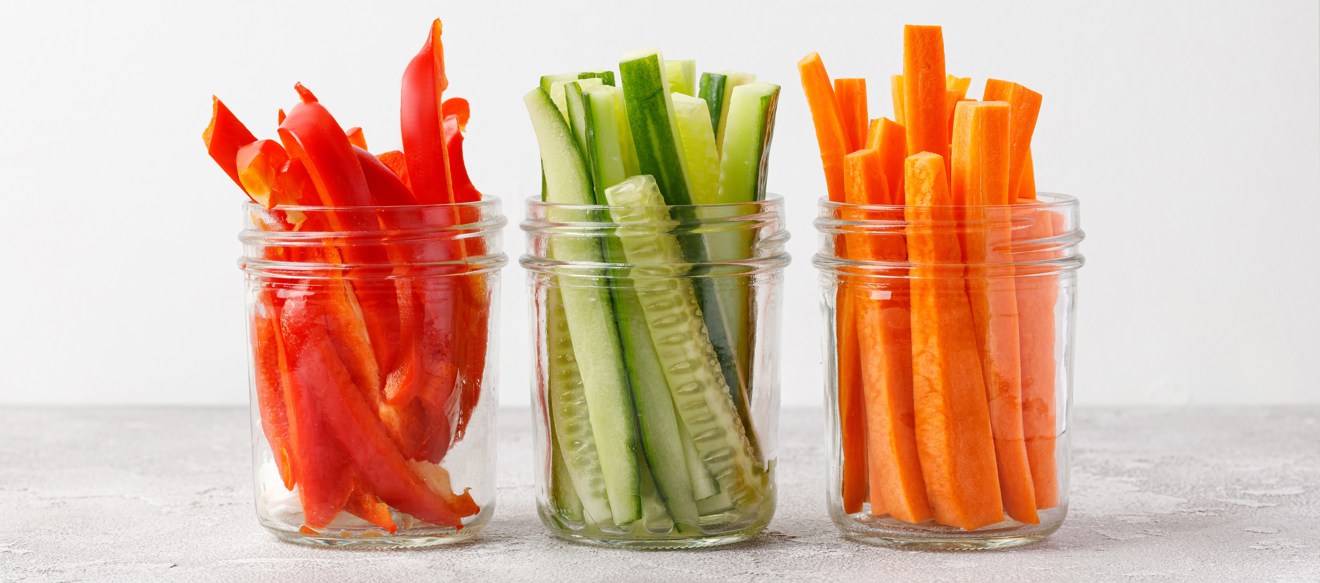 Glasburkar med stavar av paprika, gurka och morot.