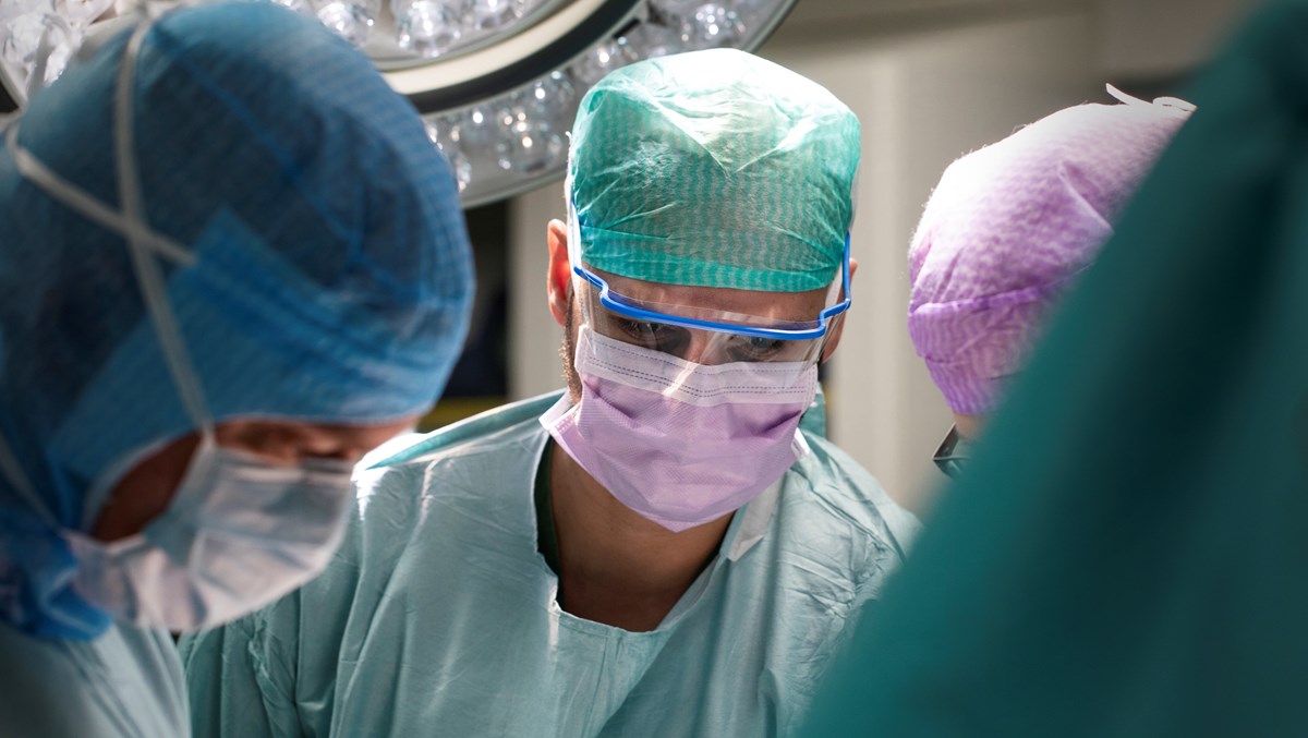 Tre läkare iklädda skyddskläder opererar
