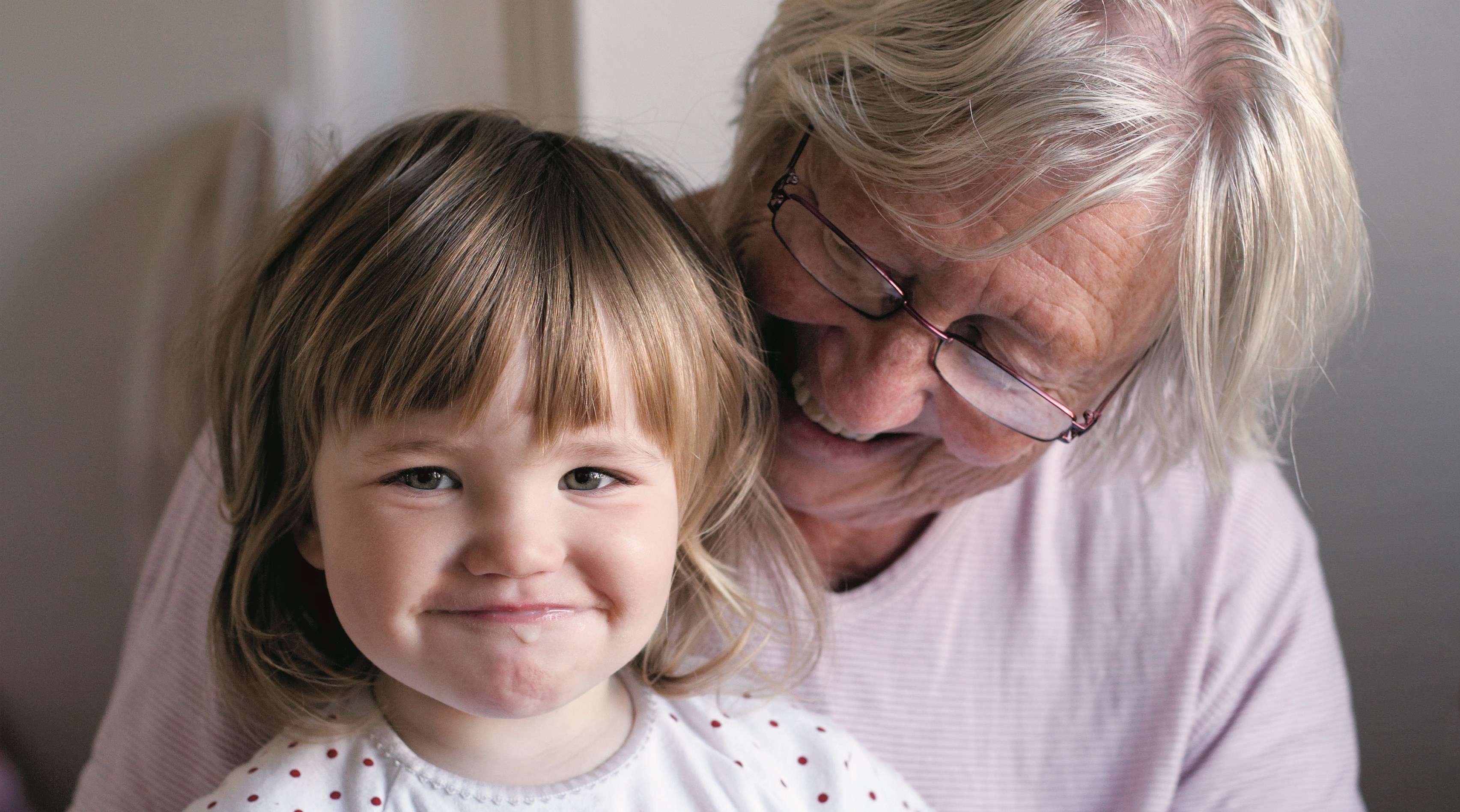 En äldre kvinna har en liten flicka i knäet.