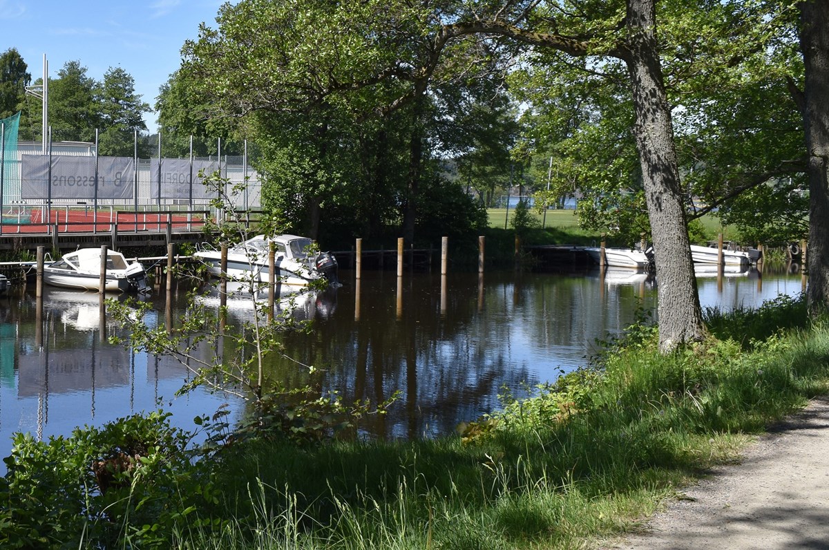 En å i kanten av Nolhagaparken. I ån ligger båtar förtöjda, och på andra sidan vattnet syns en idrottsplats.