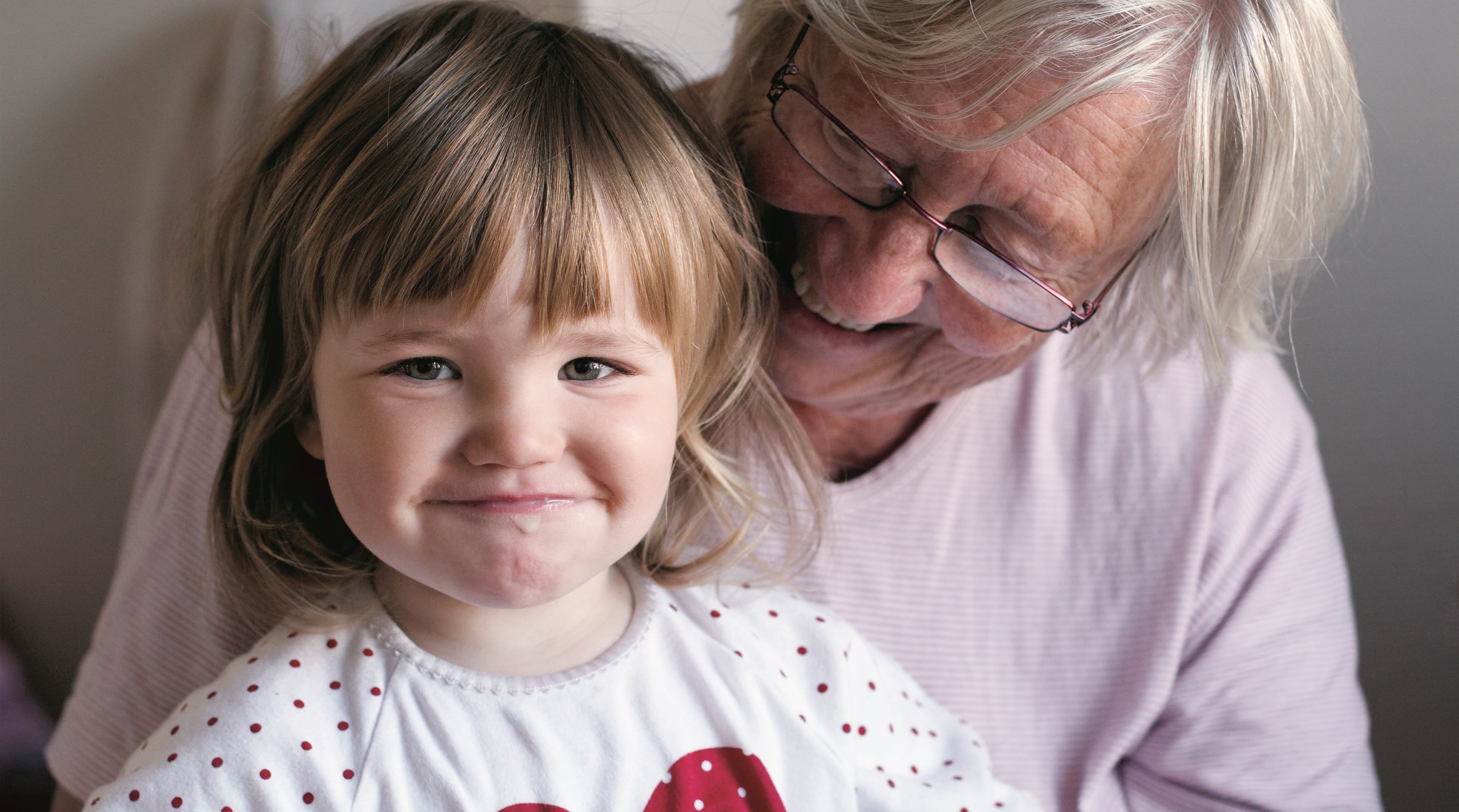 En äldre kvinna har en liten flicka i knäet.