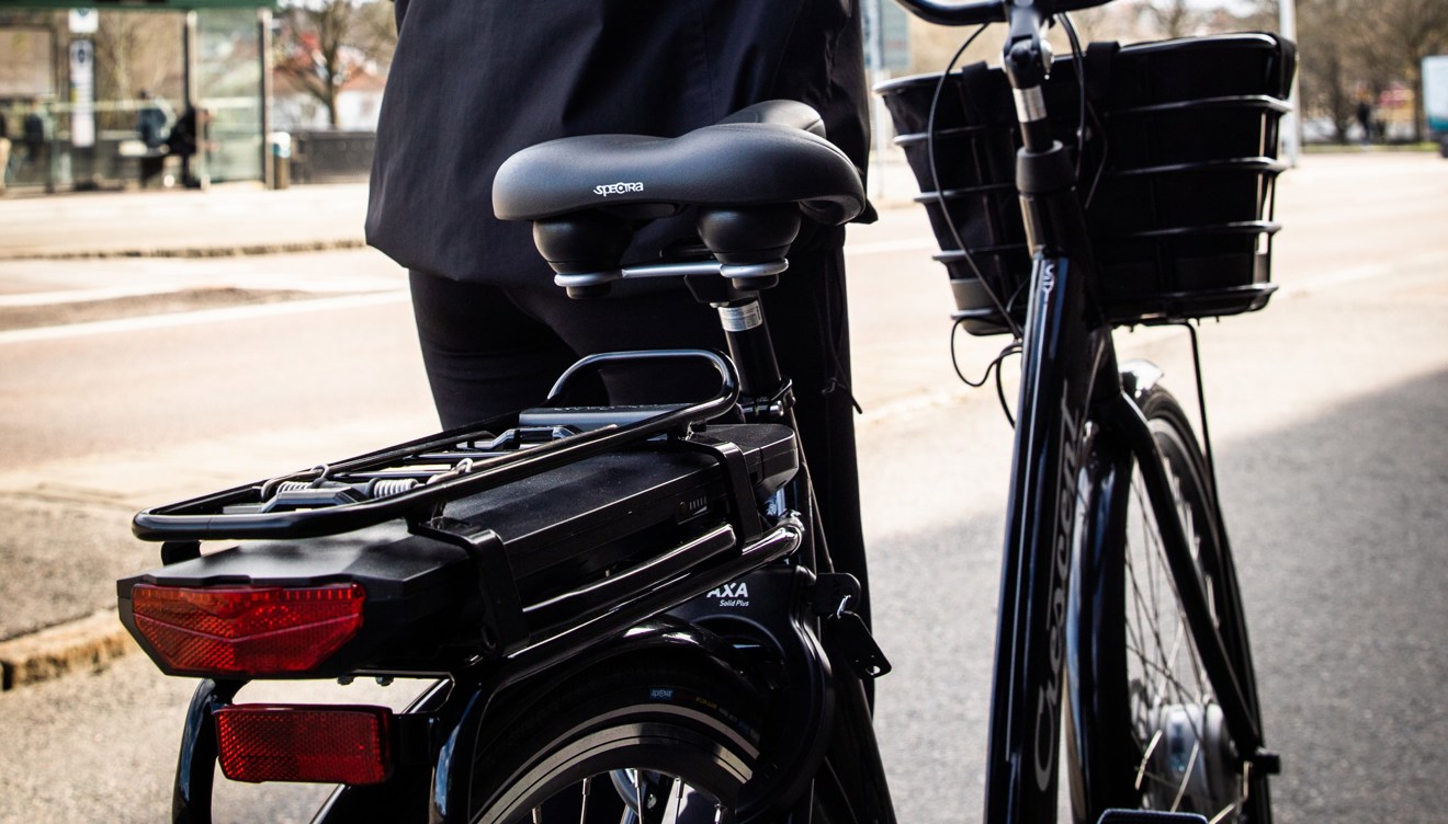 En person leder en elcykel på trottoaren