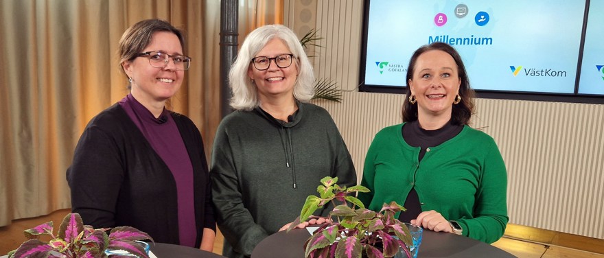 Tre kvinnor står vid runda ståbord i en föreläsningssal.