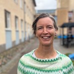 Katarina Nyström står utomhus i ett blåsigt Göteborg i november. Hon ler med hela ansiktet och ser väldigt glad ut.