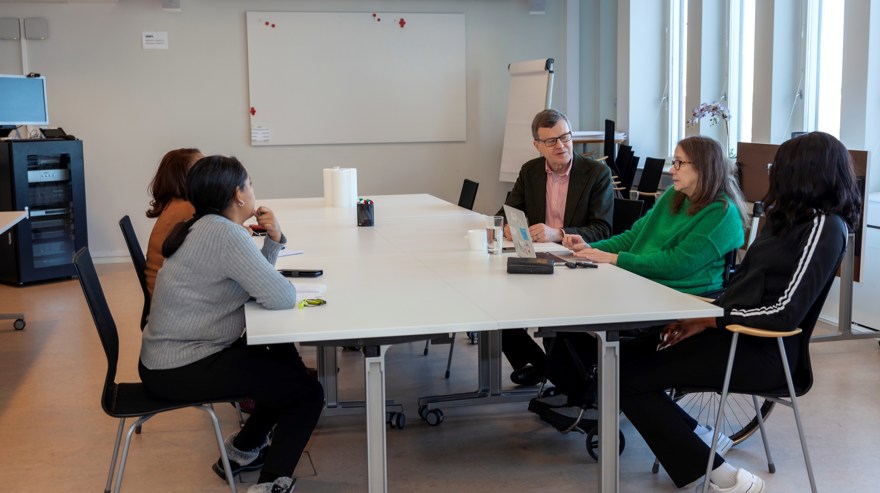 Samtal med fem personer runt ett mötesbord