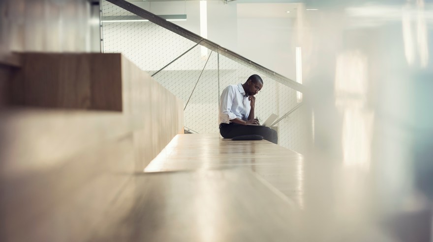 En man arbetar vid sin laptop i trappuppgången