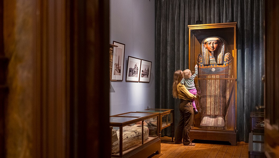 Vuxen med barn som tittar på en egyptisk sarkofag