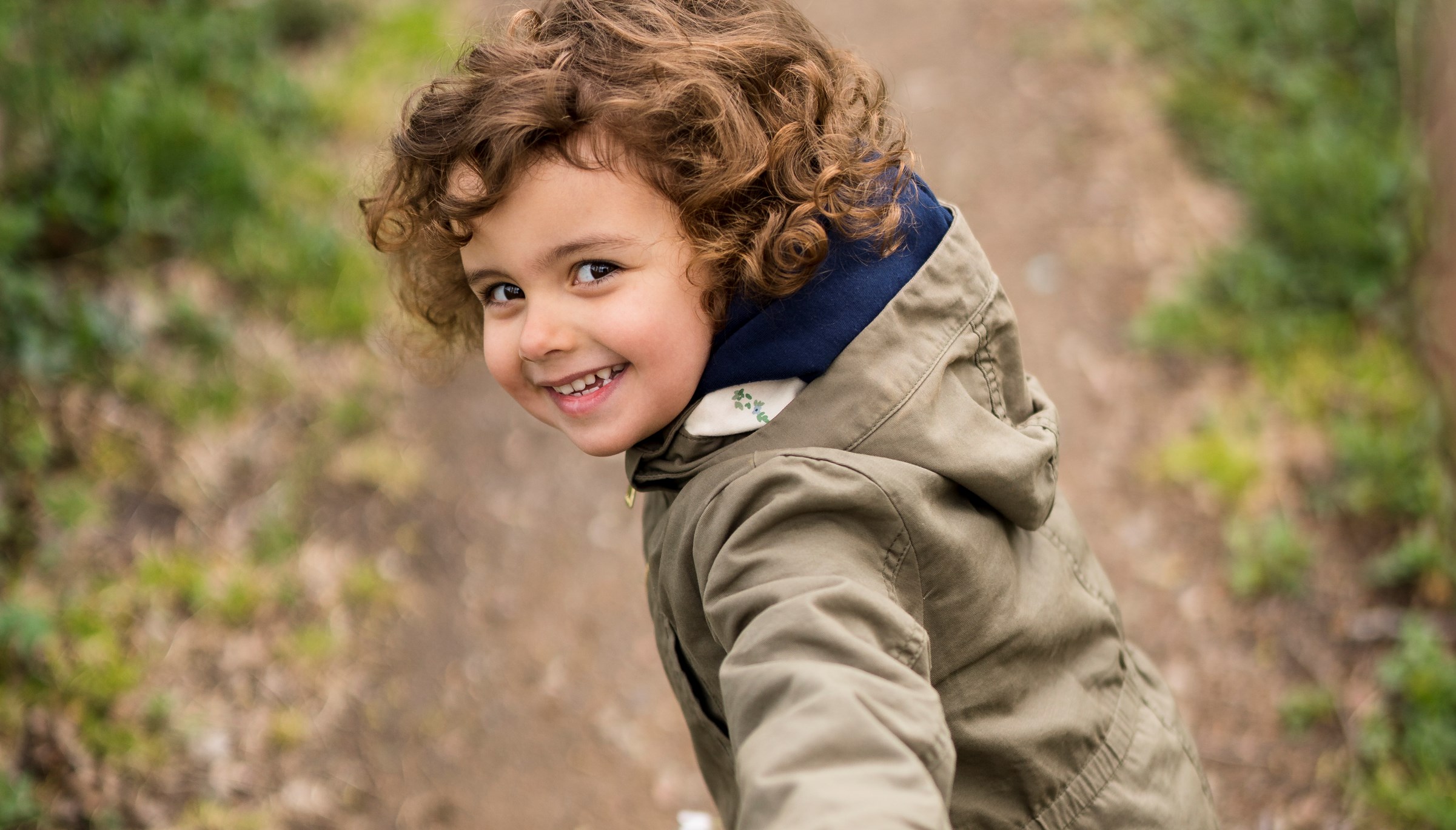 Flicka håller hand med pappa på en stig