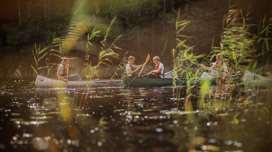 Elever i tre kanoter paddlar på vattendrag