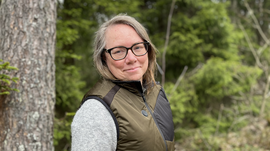 Porträtt på rektor Sofia Hottöfjäll med skog i bakgrunden