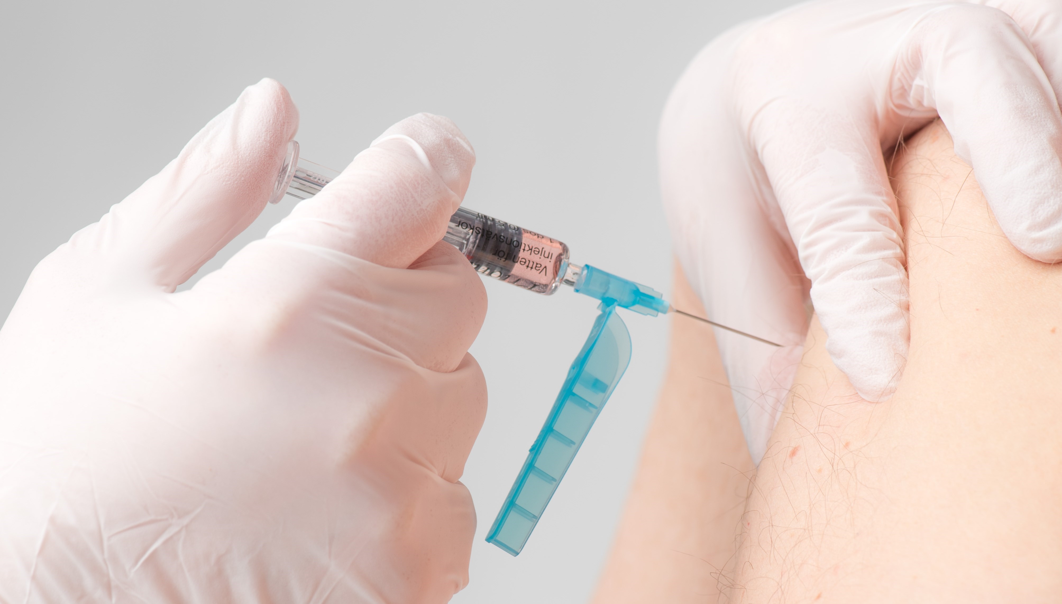 Vaccinationsspruta sticks in i armen på patient.