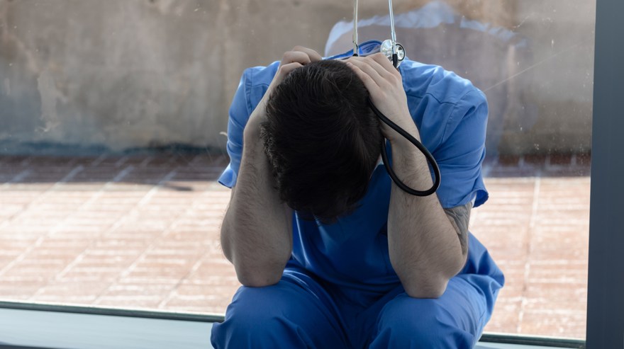 Anställd i vården som sitter ihopkurad och trött