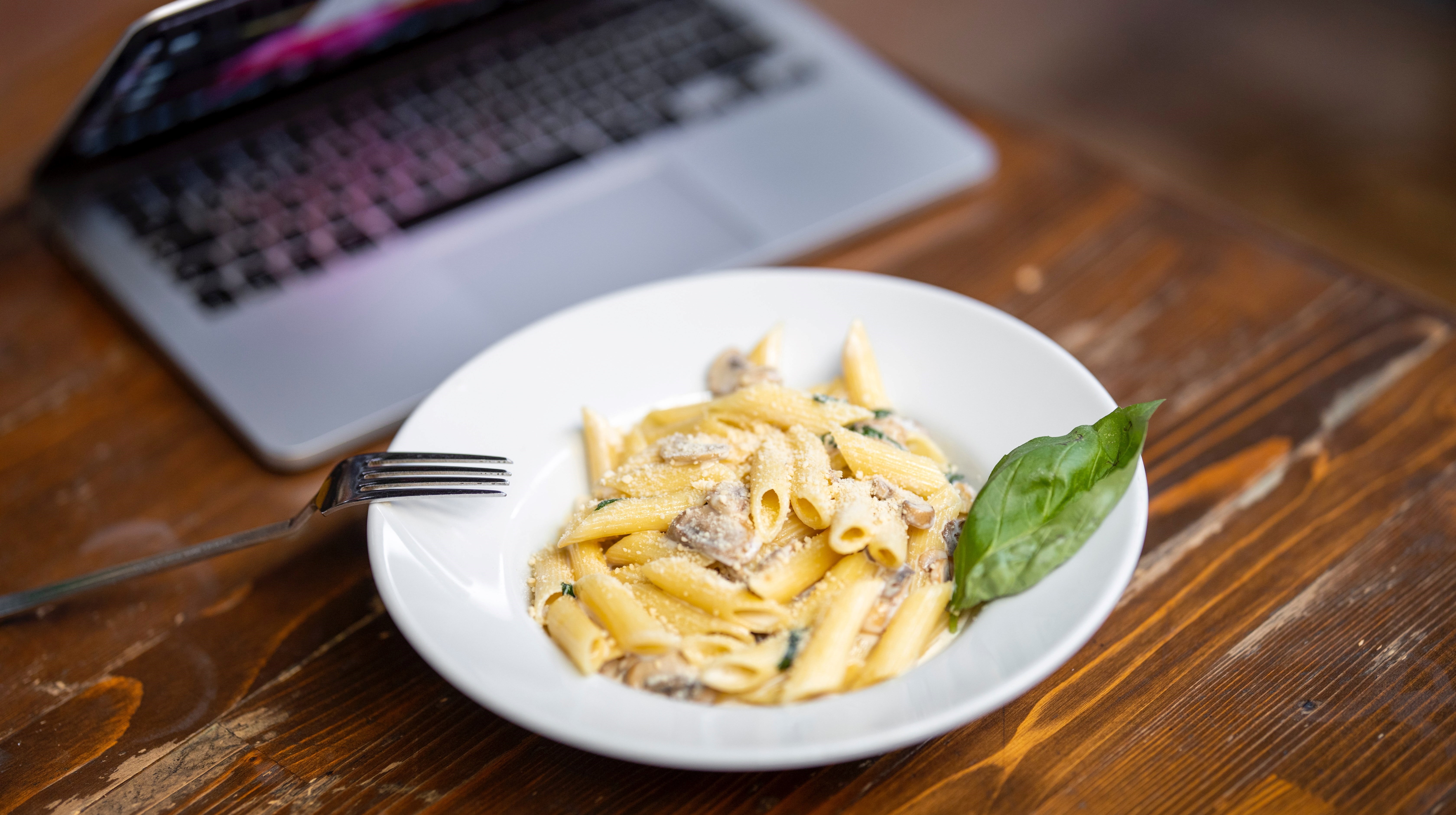 Lunchtallrik med pasta framför laptop, foto