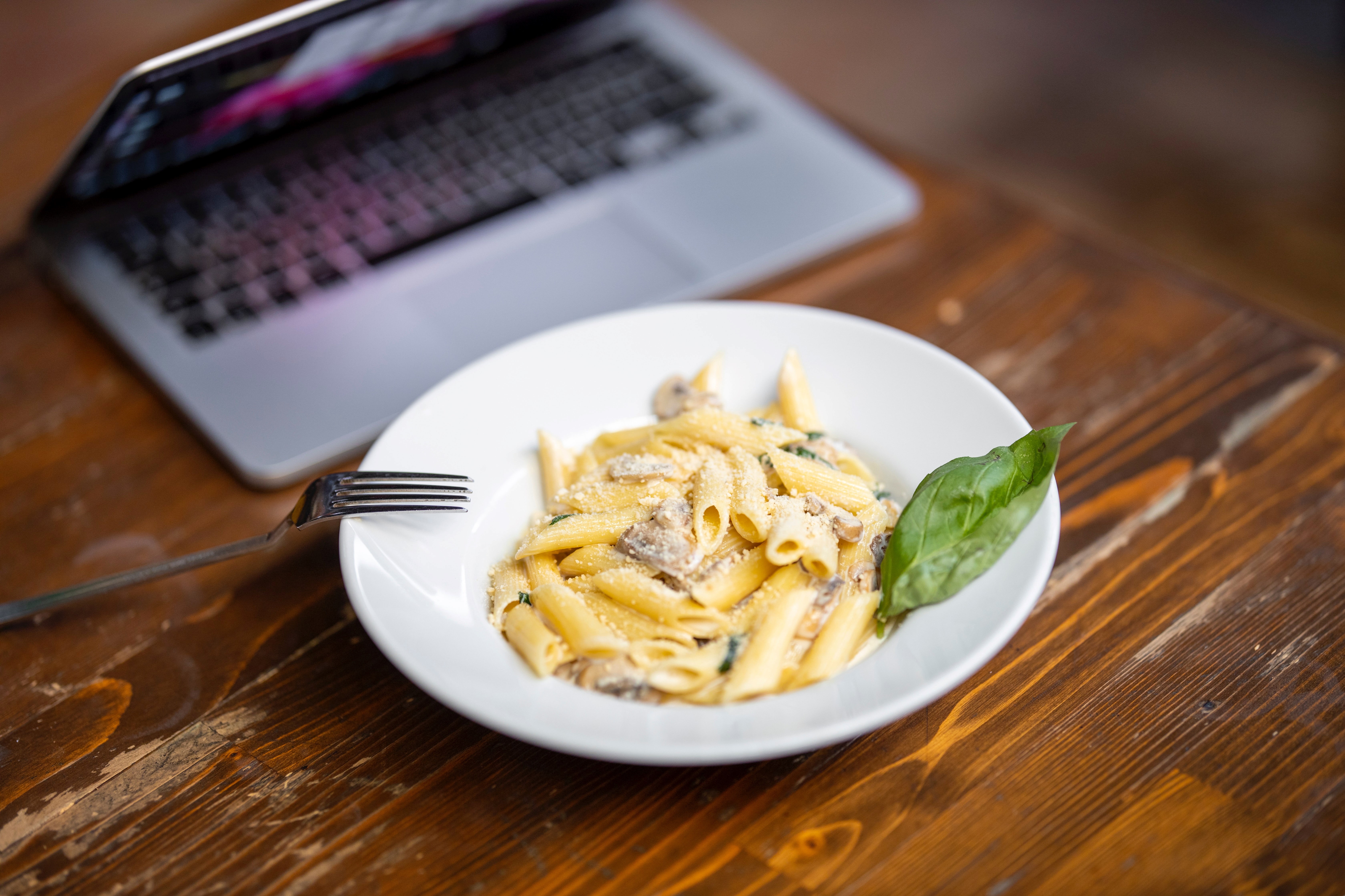 Lunchtallrik med pasta framför laptop, foto