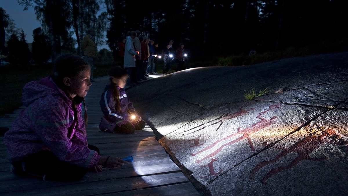 children waching rock art at night with flashlight