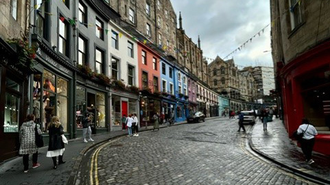 Victoria Street i Edinburgh, gatan kröker sig och är knatad av hus med färgglada fasader. Gatan är belagd med gatsten.