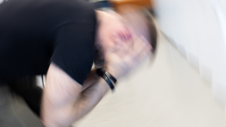 Suddig bild av person med huvudet i händerna.