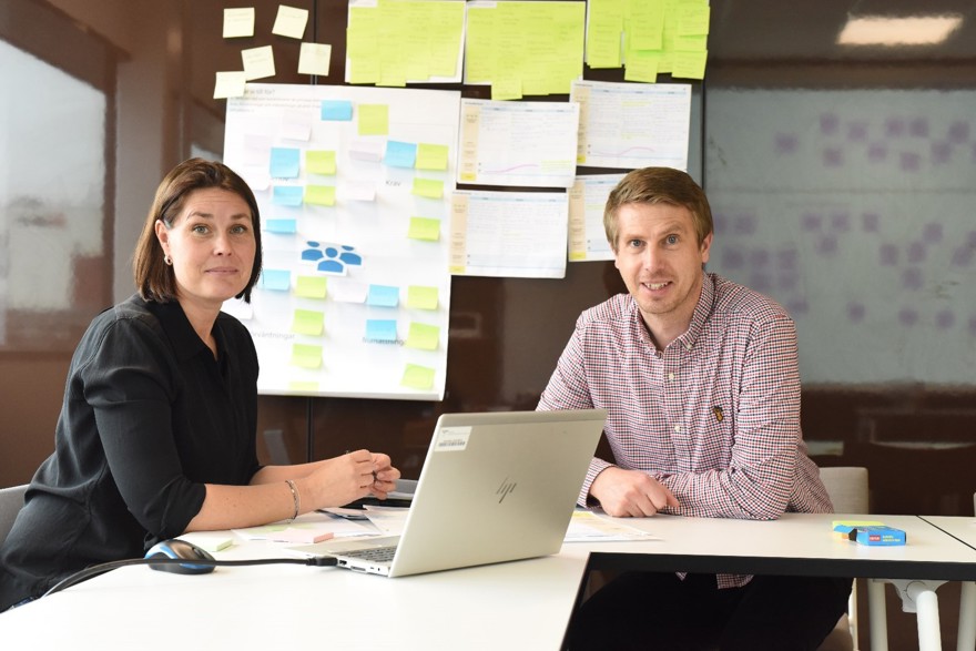 En kvinna och en man i ett kreativt möte med post-it-lappar på väggen