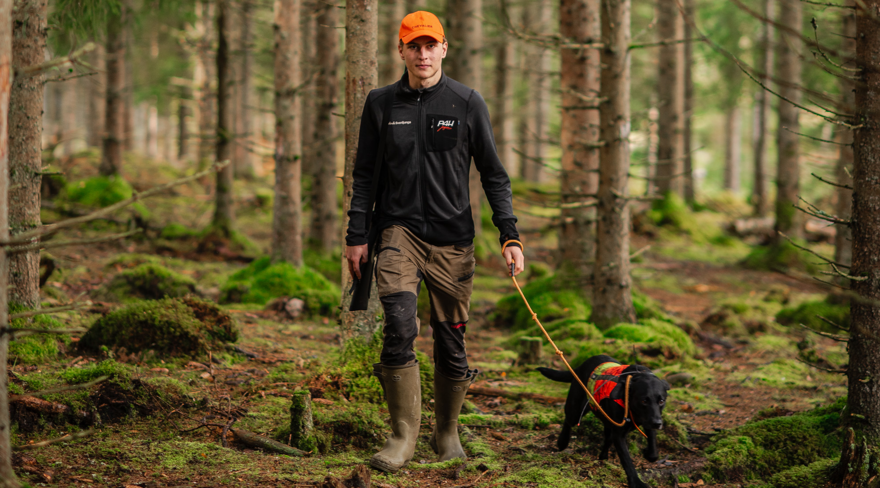 Student holding a rifle and dog.