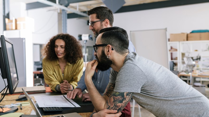 En kvinna och två män på ett kotor, som tittar på en bildskärm