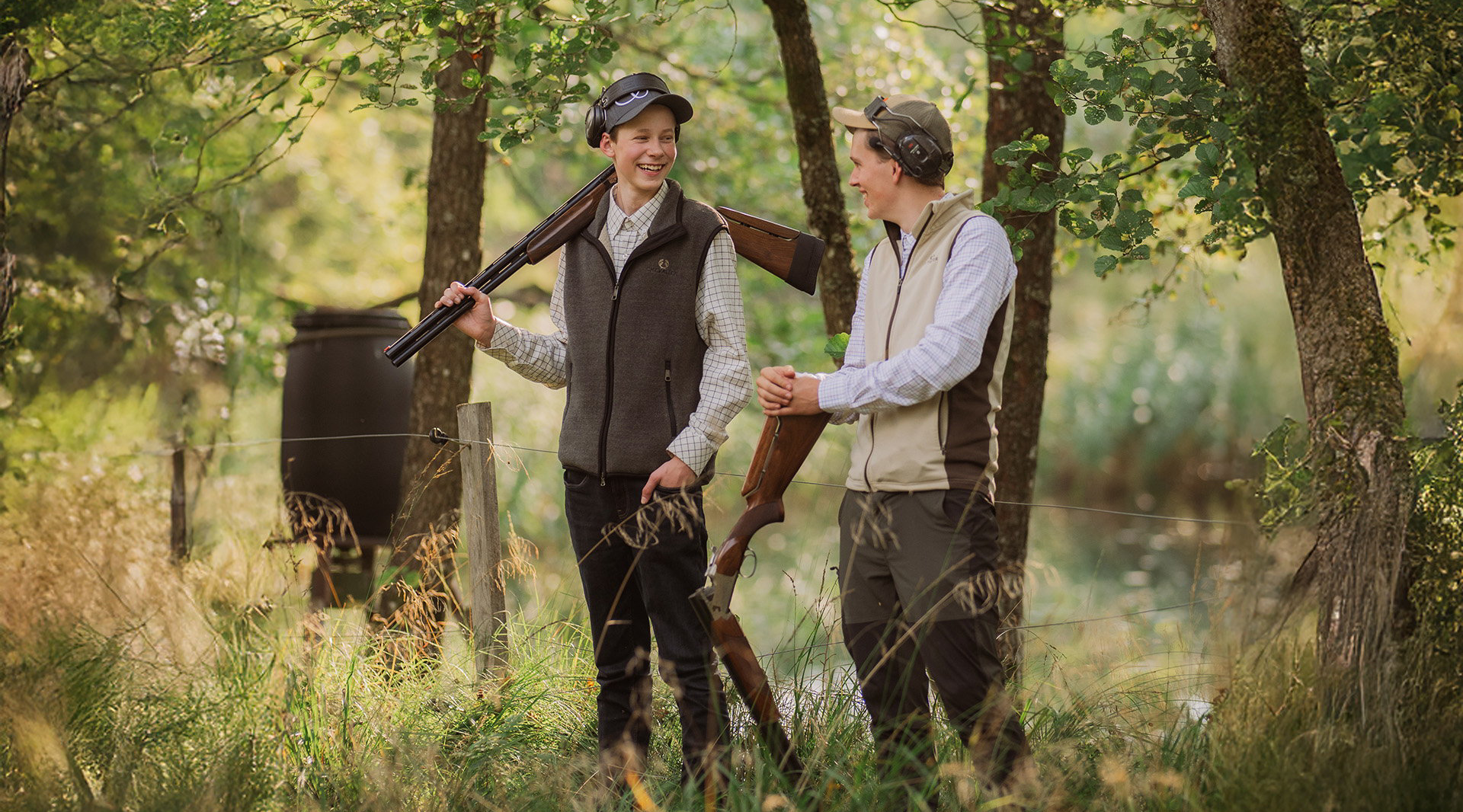 Två elever med jaktutrustning och gevär står och pratar i skogen