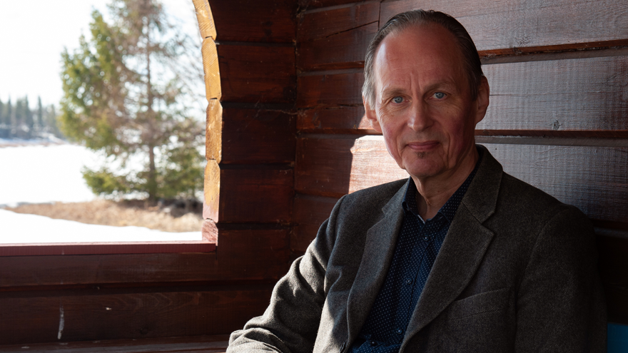 Mikael Niemi är i 65-årsåldern, han sitter inne i en stuga med timrade väggar, alldeles vid ett fönster. Han är klädd i en blå skjorta och en grå kavaj. Hans ögon är blå, håret kortklippt och kammat bakåt och han tittar mot fotografen. Utanför fönstret är det vinter, en stor gran står nära huset, det ligger snö på marken.