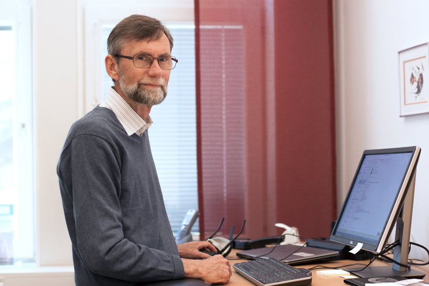 man står vid skrivbord och tittar mot kameran