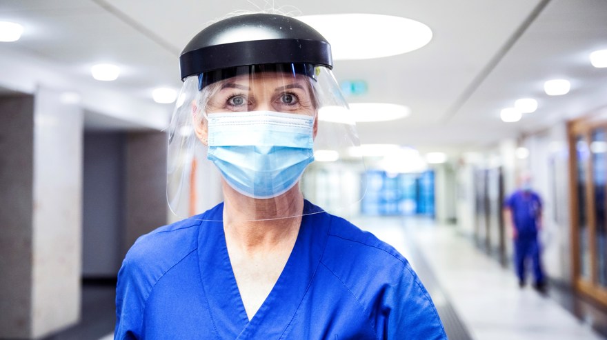 Kvinnlig vårdpersonal med visir och munskydd