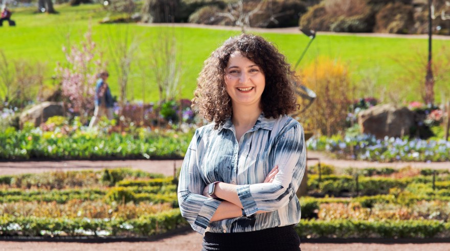 kvinna ler mot kameran rabatt med blommor i bakgrunden