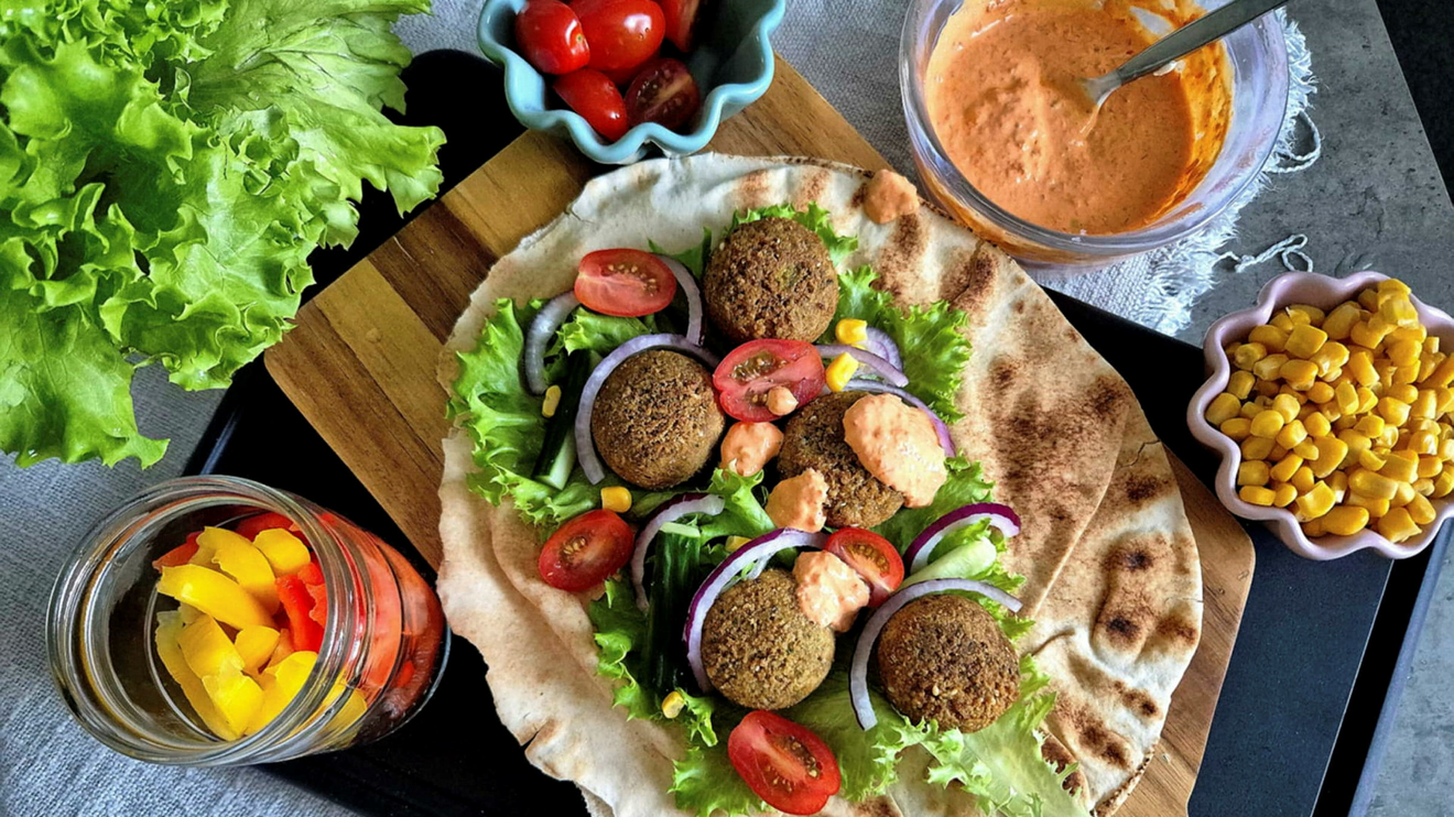 Falafel med blandade grönsaker i libabröd på en bricka av trä