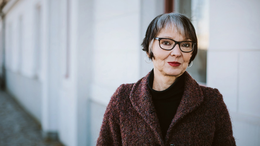 Anneli Jordahl är i medelåldern, hon har mörkt kortklippt hår med gråa inslag och bär glasögon med svarta bågar. Hennes ögon är mörka och läpparna målade i en röd kulör, i hennes öron hänger silverringar. Hon står utomhus, ett vitt hus finns bakom henne på gatan där hon står. Anneli är klädd i en svart polotröja och en rödmelerad kappa, hon tittar allvarligt på fotografen.
