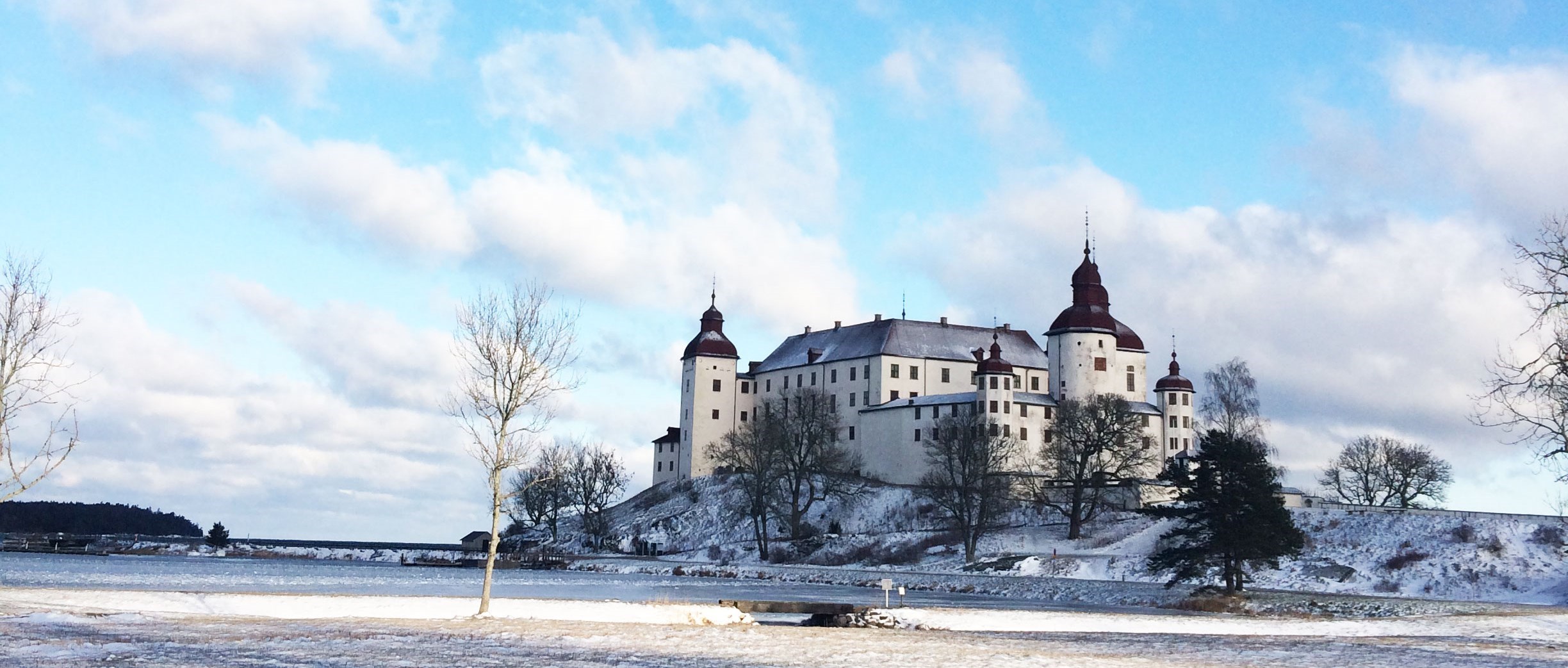 Bild på Läckö slott i vinterskrud. En vit byggnad med svart tak.