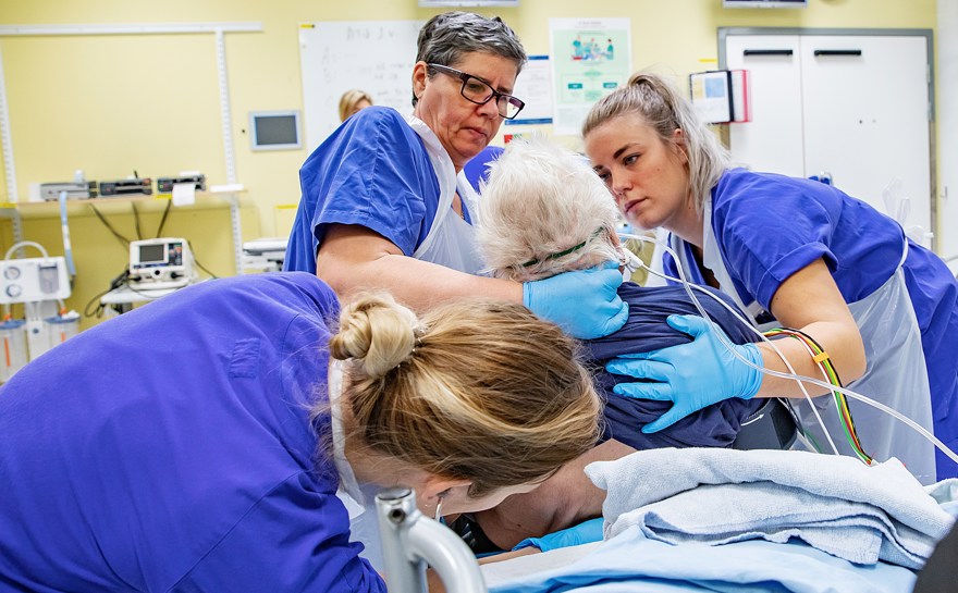 Vårdpersonal hjälper patient att sitta upp i sängen.