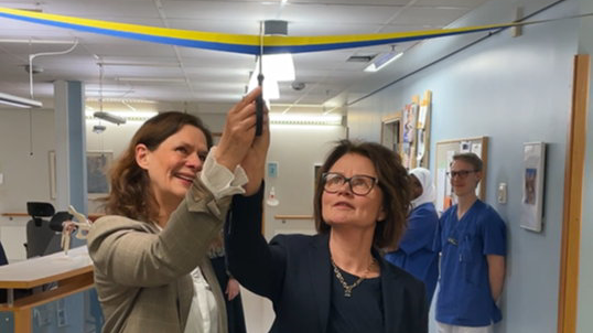 två kvinnor klipper band på invigning.