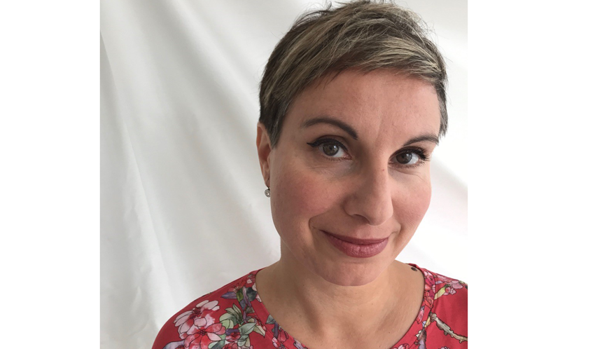 Kvinna, kort, mörkt hår med lite ljusare slingor. Röd blus med blommor.