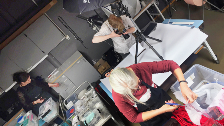Två konservatorer arbetar med att förebereda fynd för fotografering. Fotografen tar bilder på föremålen. Allt i fotoateljén.